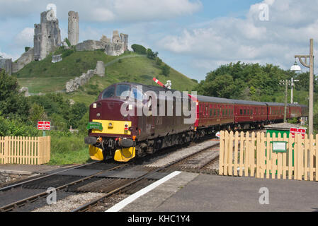 Un trainpulling diesel loin de la station de Corfe Castle dans le Dorset sur le patrimoine de Swanage Railway avec Corfe Castle en toile de fond. Banque D'Images