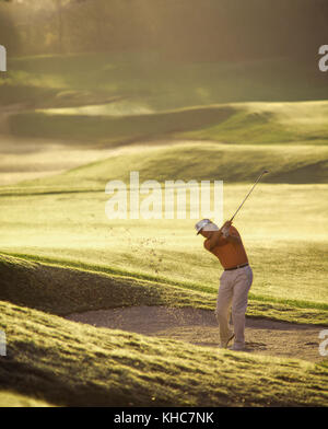 Male golfer hits à partir de la fosse de sable,tôt le matin. rétroéclairage parution modèle Banque D'Images