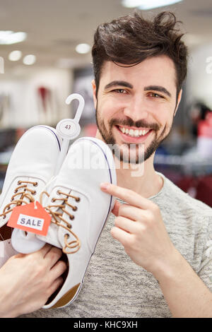 Jeune homme en tant que client l'achat de chaussures est à l'avant pour shopping Banque D'Images