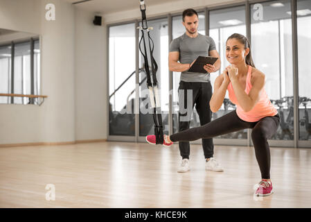 Jeune fille adultes faisant de l'exercice de la corde de suspension avec son entraîneur privé, personnel. Banque D'Images