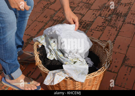 Femme avec un panier en osier le linge humide, la préparation de l'accrocher pour sécher au soleil Banque D'Images