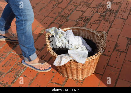 Femme avec un panier en osier le linge humide, la préparation de l'accrocher pour sécher au soleil Banque D'Images