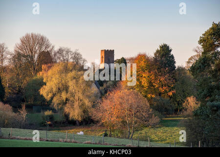 Lever du soleil d'automne à travers le village de Tadmarton avec Saint Nicholas church tower au loin. Tadmarton, Oxfordshire, UK.
