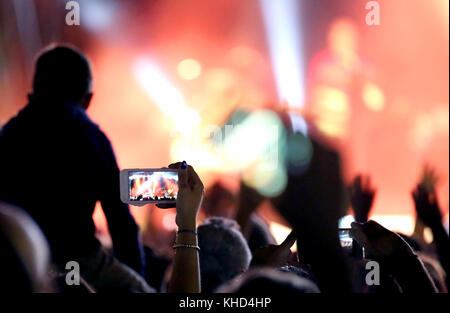 Fans qui prennent des photos et enregistrer des vidéos avec les smartphones modernes durant le concert d'un groupe de rock Banque D'Images