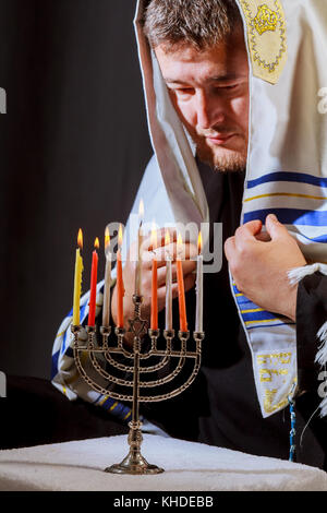 La main de l'homme en allumant des bougies sur la table servie pour la menorah hanukka bougies feux d'homme Banque D'Images