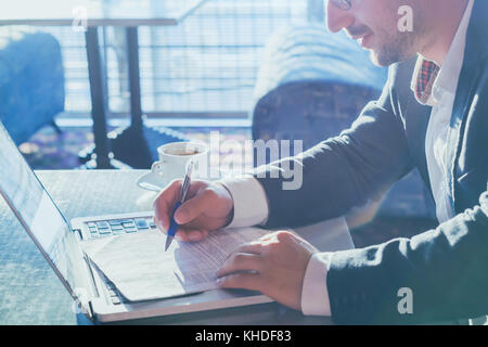 L'homme entrepreneur d'affaires travaillant avec l'ordinateur et les documents sur papier Banque D'Images