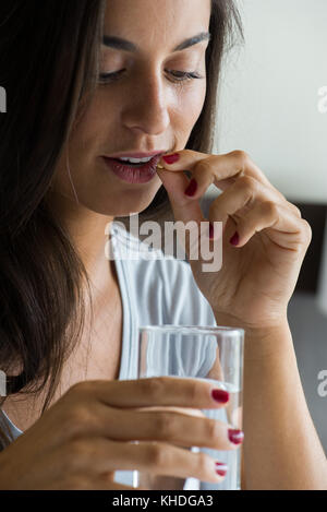 Femme de prendre la pilule à verre d'eau Banque D'Images