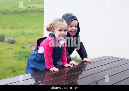 Les enfants de grimper sur une table de pique-nique humide Banque D'Images