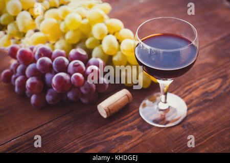 Verre de vin rouge sur la table en bois et de raisins Banque D'Images