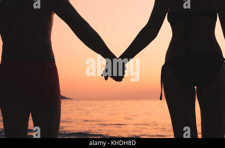 Voyage Romantique, en couple sur la plage, silhouette of man and woman holding hands at sunset Banque D'Images