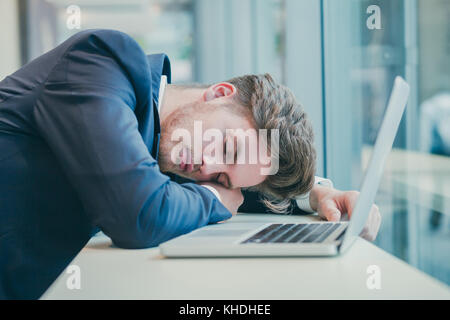 Fatigué businessman sleeping près de l'ordinateur Banque D'Images