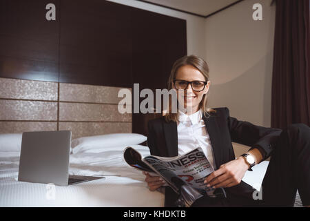 Businesswoman reading magazine dans l'hôtel Banque D'Images