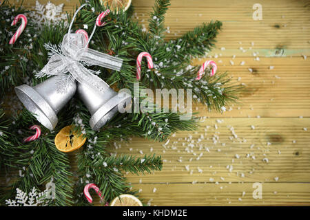 La saison d'hiver photographie image avec des branches d'arbre sapin pin vert avec Bell et des cannes de bonbon sur la table en bois avec de la neige saupoudrée Banque D'Images