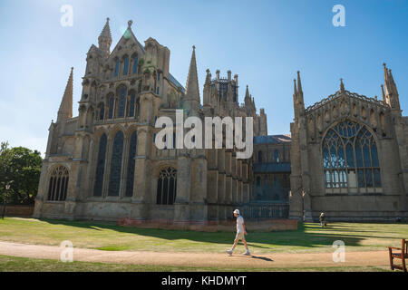 Ely Cathedral UK, un visiteur à Ely marche le long de l'extrémité est de la cathédrale médiévale de la ville, Cambridgeshire, Angleterre, Royaume-Uni Banque D'Images