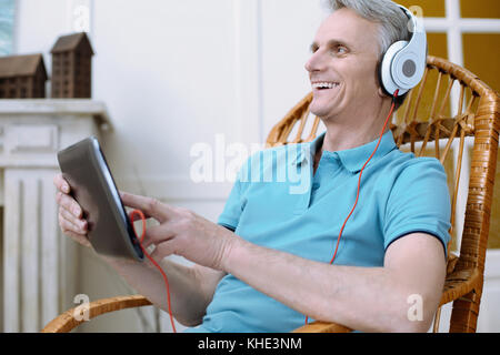 Vieil homme gai holding a tablet Banque D'Images