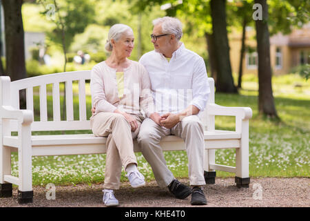 Happy senior couple sitting on bench at park Banque D'Images