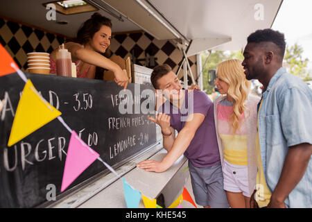 Vendeur menu montrant aux clients au camion alimentaire Banque D'Images