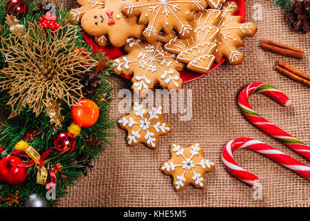 Gingerbread cookies de Noël dans la maison de la plaque rouge avec des branches de sapin de noël et nouvel an décor sur table avec nappe de toile. merry christma Banque D'Images