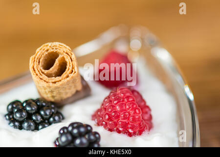 Dessert sucré avec des fruits et de détail. bokeh bol avec du yogourt, framboises, mûres et biscuit sur fond flou. Banque D'Images