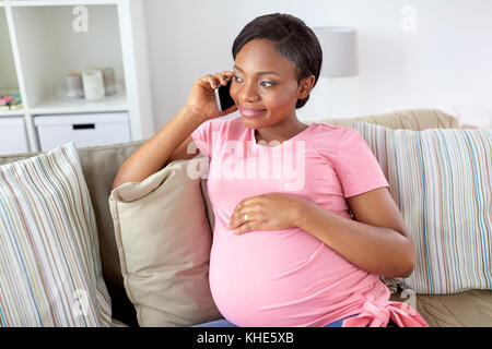 Happy pregnant woman calling sur smartphone à la maison Banque D'Images