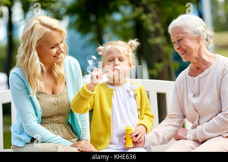 Happy Family blowing soap Bubbles at park Banque D'Images