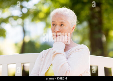 Sad senior woman sitting on bench at summer park Banque D'Images