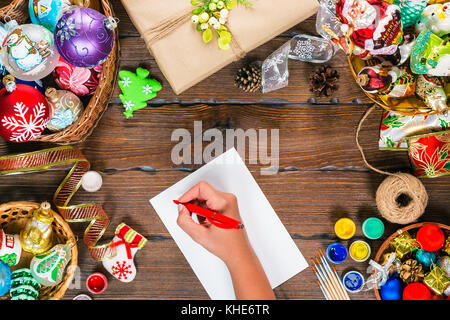 Fond de Noël avec des décorations, boules, cadeaux et jouets sur planche de bois. fille main écrit une lettre Cher Père Noël. belle idée noël fo Banque D'Images