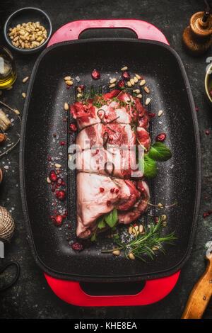 Rôti d'épaule d'agneau cru avec string , fines herbes et épices sur rouge plaque de cuisson, vue du dessus de la viande.. Banque D'Images