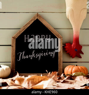 Un tableau noir en forme de maison avec le texte joyeux thanksgiving écrit en C, un drôle de plumés en caoutchouc de la Turquie, quelques feuilles de l'automne et quelques citrouilles contre Banque D'Images