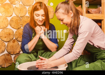 La femelle potter enseigne une red-haired woman à moule correctement un grand bol d'argile sur un tour de potier. formation potter pour travailler sur un tour de potier, tr Banque D'Images