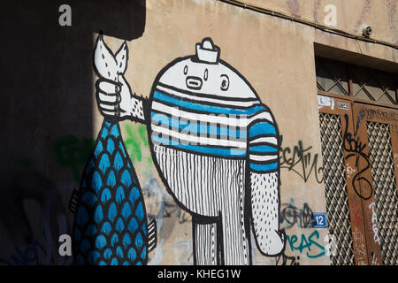 Graffiti d'un humanoïde tenant un poisson dans une petite rue dans la région de Plaka à Athènes, Grèce Banque D'Images