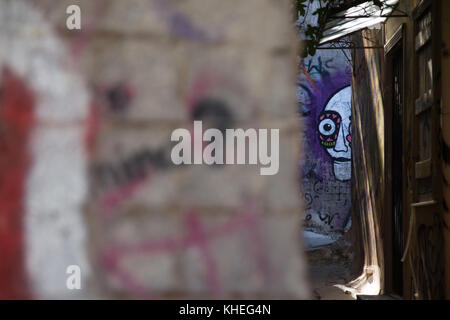 Le graffiti d'un visage effrayant à travers une ouverture dans une petite rue dans la région de Plaka d'Athènes, Grèce Banque D'Images