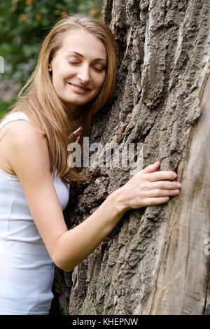 Young woman hugging big tree Banque D'Images