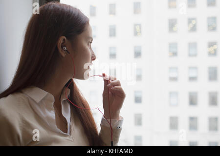 Young Woman talking on smartphone via la prise casque Banque D'Images