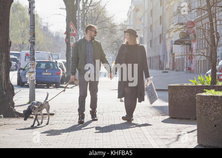 Young couple holding hands en se promenant son chien Banque D'Images