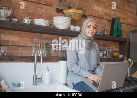 Femme musulmane de travailler à domicile sur son ordinateur portable Banque D'Images