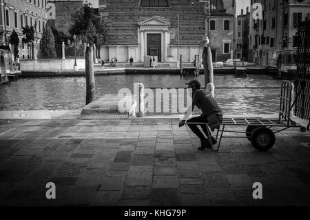 Fin de la journée de travail à Venise pour cette livraison homme ou est-il juste d'attendre la prochaine charge à déposer pour lui d'offrir. La photographie de rue Banque D'Images