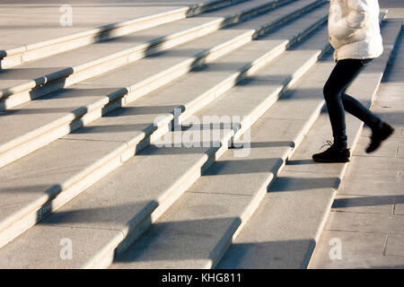 Une adolescente qui monte les escaliers dans le motion blur et les ombres de personnes à la suite , sur grand escalier extérieur public Banque D'Images