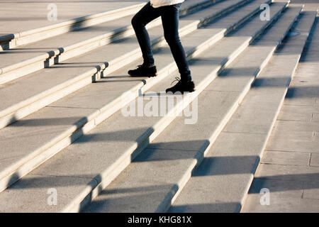 Une adolescente qui monte les escaliers dans le motion blur et les ombres de personnes à la suite , sur grand escalier extérieur public Banque D'Images