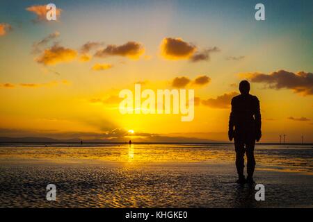 Crosby, Merseyside. Coucher de soleil sur Crosby. 16 novembre 2017. Météo britannique. Après une journée glaciale, sur la côte nord-ouest de l'Angleterre, un superbe coucher du soleil tombe dans l'horizon pour créer des silhouettes de Sir Antony Gormley est "un autre endroit" Iron Men art installation sur les rives du Crosby Beach dans le Merseyside. "Un autre endroit" se compose de 100 fonte, life-size figures réparties le long de trois kilomètres de l'estran, qui s'étend près d'un kilomètre au large. Credit : Cernan Elias/Alamy Live News Banque D'Images