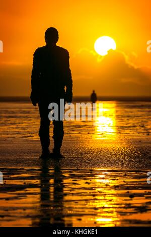 Crosby, Merseyside. Coucher de soleil sur Crosby. 16 novembre 2017. Météo britannique. Après une journée glaciale, sur la côte nord-ouest de l'Angleterre, un superbe coucher du soleil tombe dans l'horizon pour créer des silhouettes de Sir Antony Gormley est "un autre endroit" Iron Men art installation sur les rives du Crosby Beach dans le Merseyside. "Un autre endroit" se compose de 100 fonte, life-size figures réparties le long de trois kilomètres de l'estran, qui s'étend près d'un kilomètre au large. Credit : Cernan Elias/Alamy Live News Banque D'Images