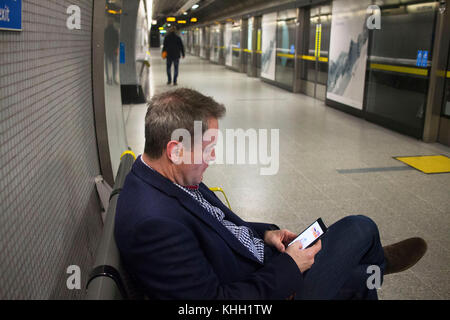 Londres, Angleterre, Royaume-Uni. 11 novembre 2017. Homme est assis seul sur son téléphone sur la plate-forme pour la nuit d'attente ©tube Sian Reekie Banque D'Images