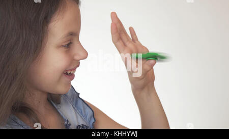 Belle cheerful girl Playing with green fidget spinner sur fond blanc Banque D'Images