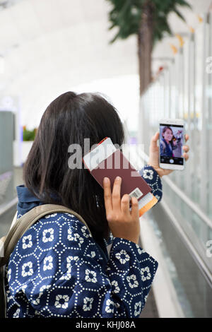 Les femmes thaïlandaises voyageur smartphone utiliser prendre photo avec billet et passeport à l'aéroport international Suvarnabhumi de Bangkok, Thaïlande. Banque D'Images