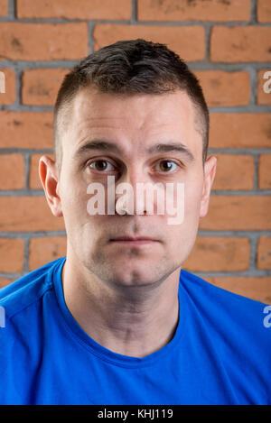 Brunet dans l'homme Tee-shirt bleu sur fond brique Banque D'Images