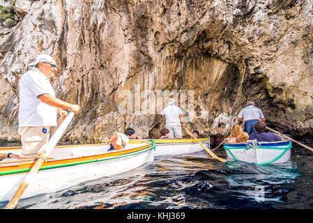 Une ligne de touristes attendent dans un petit bateau pour entrer dans la célèbre Grotte bleue sur l'île de Capri en Italie Banque D'Images