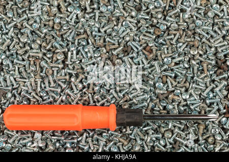 Tournevis orange se trouve sur un tas de boulons.Avec l'espace pour le texte. Vue de dessus Banque D'Images