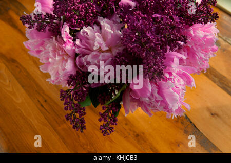 Vue de dessus de l'embrayage rouge, bordeaux et fleurs roses sur une table en bois. Banque D'Images