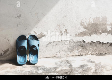 Tongs bleu sur l'ancien mur de béton. Banque D'Images