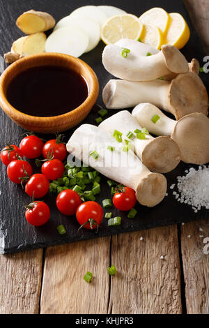 Roi des champignons crus trompette avec des ingrédients pour la cuisine gros plan sur la table. vertical Banque D'Images